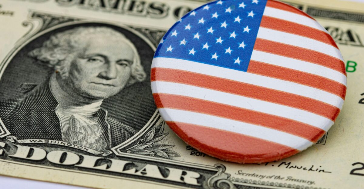 a button with the american flag on it sitting on top of a hundred dollar bill