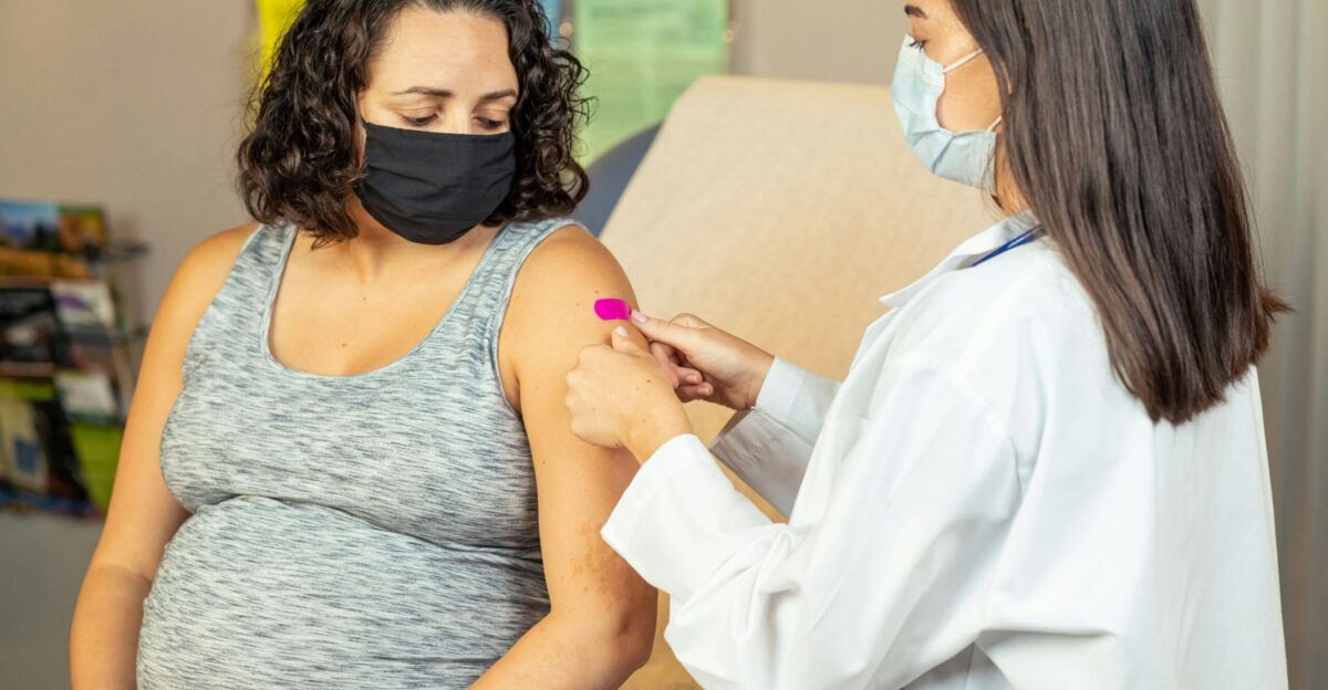 a pregnant woman wearing a face mask is being examined by a doctor