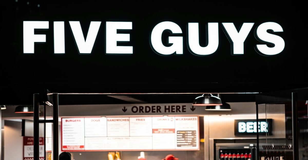 a five guys restaurant is lit up at night