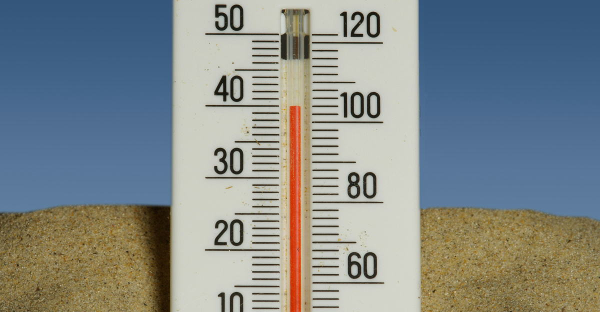 A thermometer in the sand with a blue sky in the background