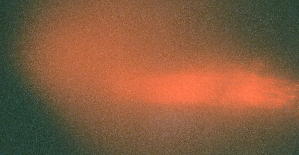 An orange glow against a dark, grainy backdrop.