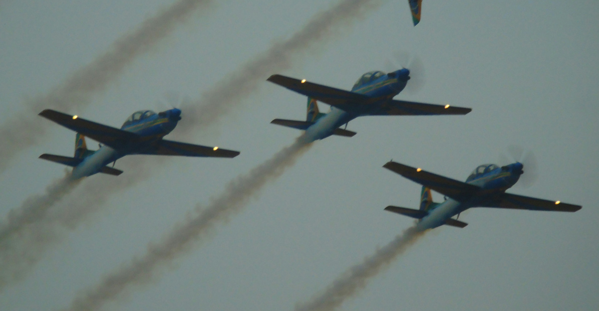 Six airplanes fly in formation, leaving smoke trails.
