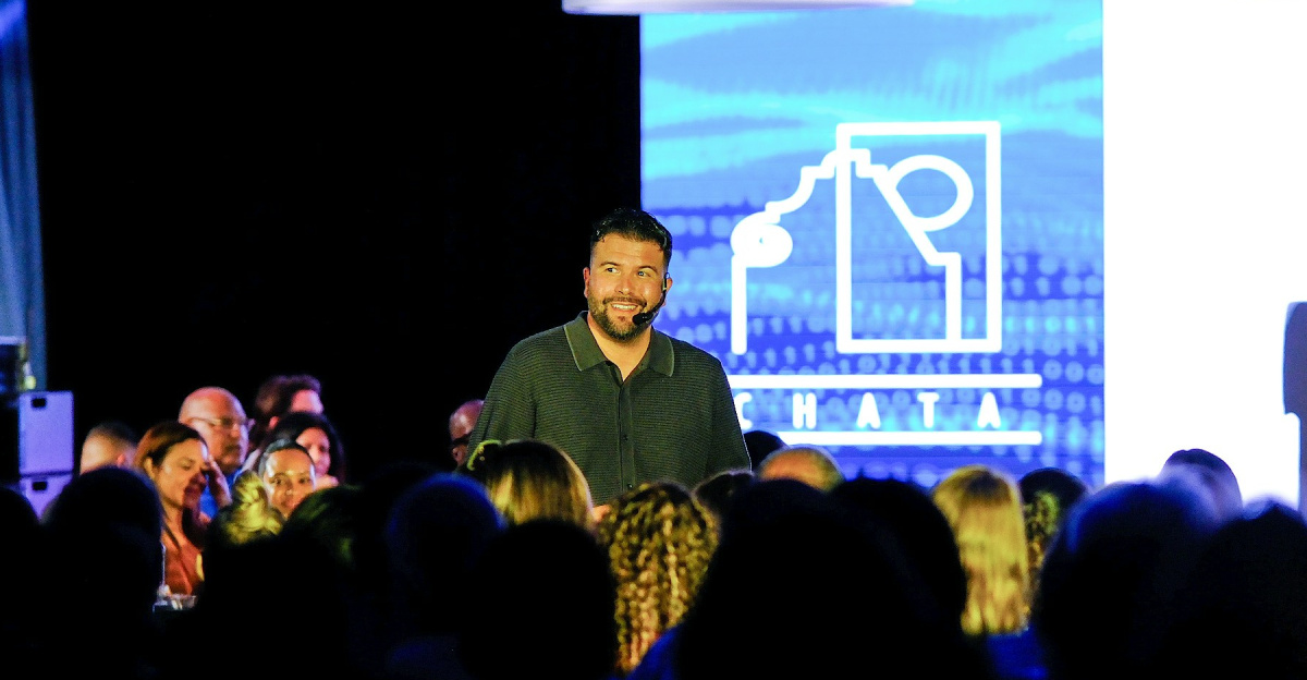 Man speaking on stage with audience watching