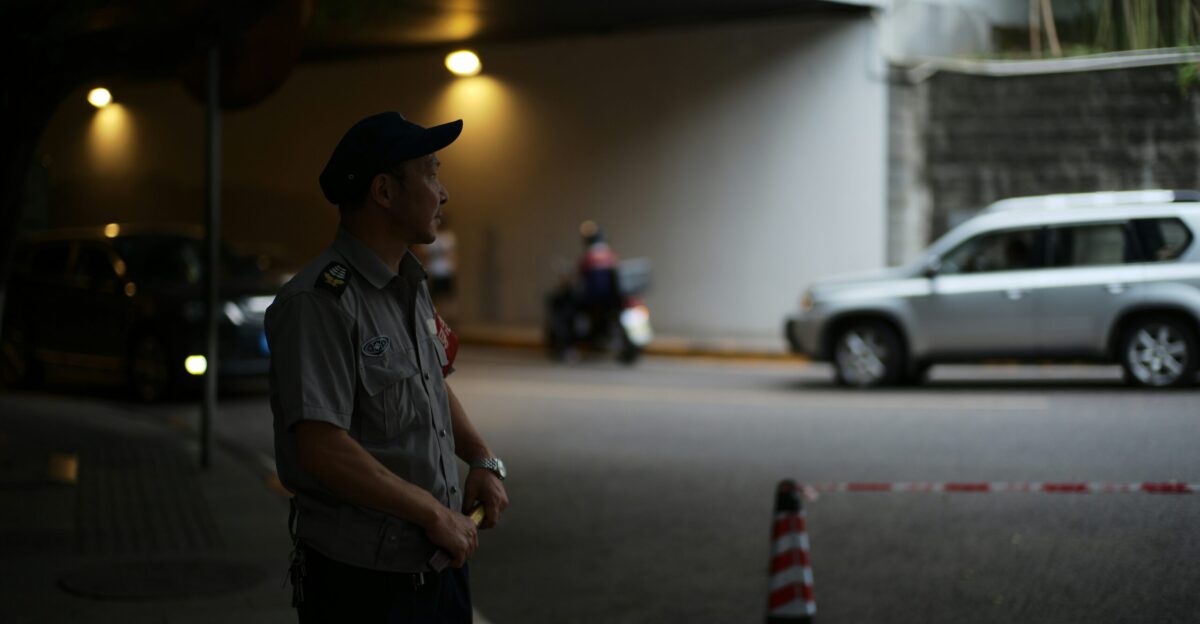 Security guard stands near tunnel entrance with vehicles