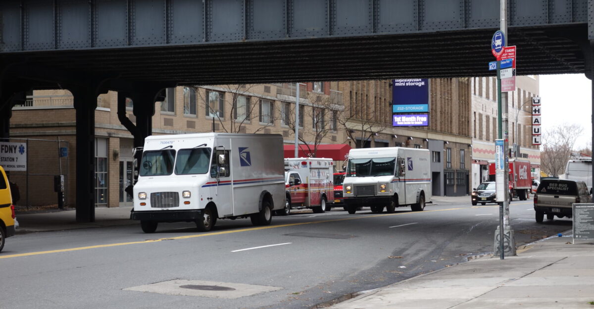 Two USPS vans traveling east under Section 2 of the High Line on West 23rd Street west of 10th Avenue in Chelsea Manhattan