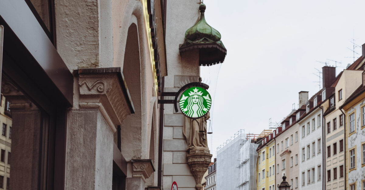 The sign of a Starbucks which depicts a siren in front of a archangel Michael statue in the Sendlinger Stra e Munich